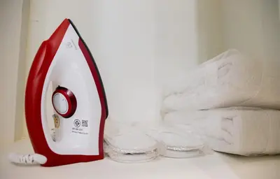 a red and white towel iron next to a stack of towels at Cozy Stay Inn in Bang Kapi