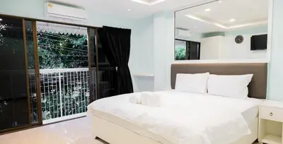 a bedroom with a white bed and a large window at Cozy Stay Inn in Bang Kapi