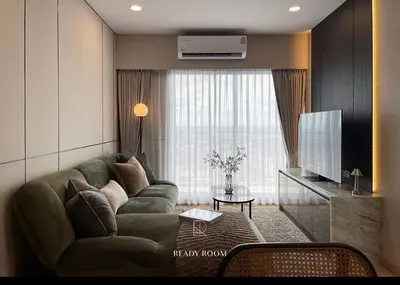 a living room with a green couch and a television at Luxury room in Ban Khlong Bang Chak
