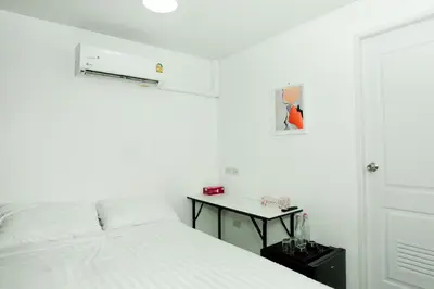 a white bedroom with a bed and a table at The Hostel Era in Bangkok