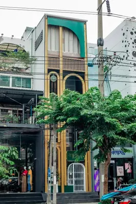 a yellow and green building with a tree in front of it at The Hostel Era in Bangkok