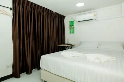 a bedroom with a white bed with brown curtains at The Hostel Era in Bangkok