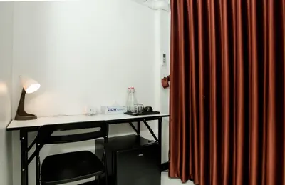 a desk with a lamp and a red curtain at The Hostel Era in Bangkok