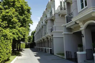 a row of buildings on a street with trees at Sukhumvit 16 Townhouses, InHome Luxury Residences in Bangkok