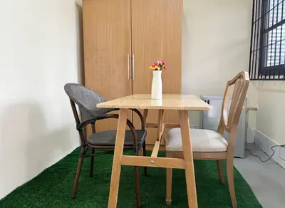 a table with chairs and a vase with flowers on it at Apamet Hotel Sukhumvit 55 in Khlong Toei