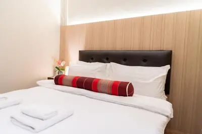 a bed with a red pillow on top of it at Pillow BKK Bliss townhome 5BR,7TL near BTS&MRT QSCC in Khlong Toei