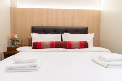 a large white bed with a red pillow on it at Pillow BKK Bliss townhome 5BR,7TL near BTS&MRT QSCC in Khlong Toei