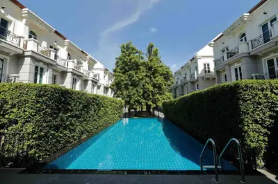 a swimming pool in front of a building with bushes at 3BR Sukhumvit Townhouse, close to Emsphere and BTS MRT in Bangkok