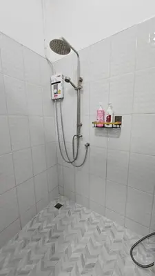 a shower in a white tiled bathroom at NAN Square in Pratunam