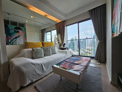 a living room with a couch and a large window at 1BR at ThongLor BTS overlooking city with Workspace in Bangkok