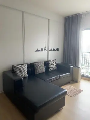 a living room with a black couch and a window at Luxury Condominium in Bangkok