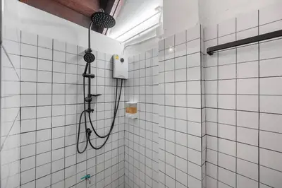 a shower in a bathroom with white tiles at Sorrento Bangkok Old Town MRT Samyot in Bangkok