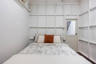 a small bedroom with a bed with white walls at Sorrento Bangkok Old Town MRT Samyot in Bangkok