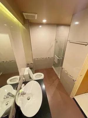 a bathroom with two sinks and a toilet and a shower at Le Ram Hotel No window in Bangkok