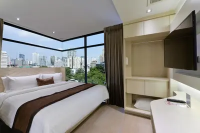 a bedroom with a large bed and a large window at Syama Mansion Phromphong in Bangkok