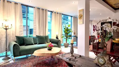 a living room with a green couch and a table at Syama Mansion Phromphong in Bangkok