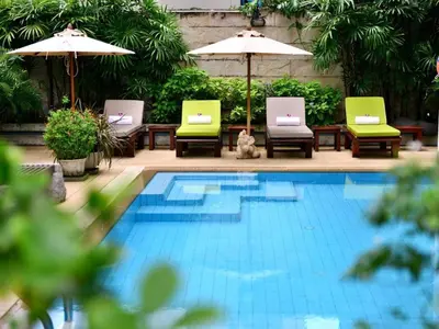 a swimming pool with chairs and umbrellas next to at St. James Hotel in Bangkok