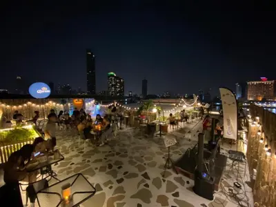 a group of people sitting on a rooftop at night at KOWTHA RIVERTEL in Bangkok