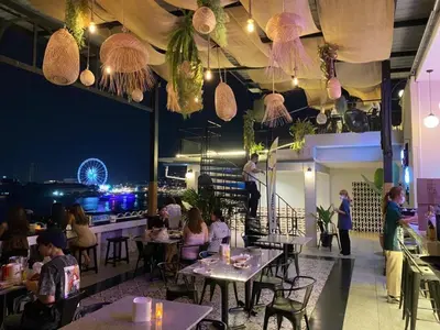 a restaurant with people sitting at tables at night at KOWTHA RIVERTEL in Bangkok