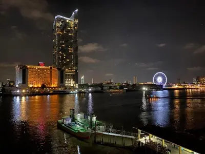 a boat in a river with a city at night at KOWTHA RIVERTEL in Bangkok