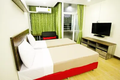 a hotel room with two beds and a television at AC Sport Village in Bangkok