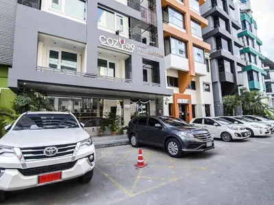 a row of cars parked in a parking lot in front of a building at Cozy At 9 Hotel And Kitchen in Bangkok