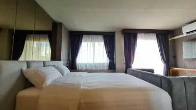 a bedroom with a large bed and two windows at We Hotel in Ban Bang Toei (1)