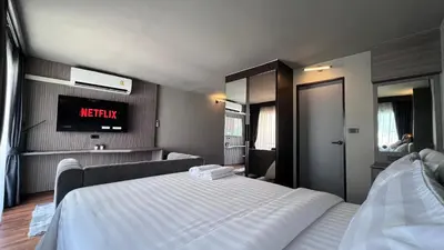 a bedroom with a white bed and a tv at We Hotel in Ban Bang Toei (1)