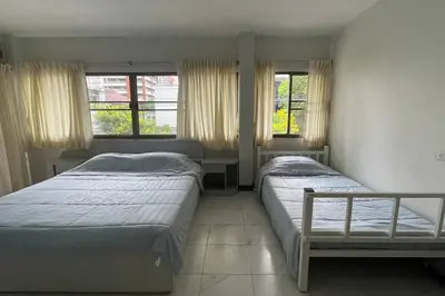 a bedroom with two beds and two windows at Manoo House E in Pratunam