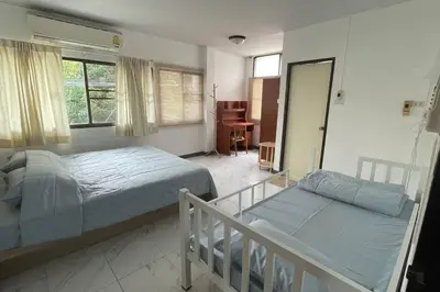 a bedroom with two beds and a balcony with a desk at Manoo House E in Pratunam