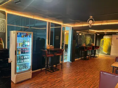 a bar with a refrigerator and some tables and chairs at Lemon Tree Hostel Khaosan in Bangkok