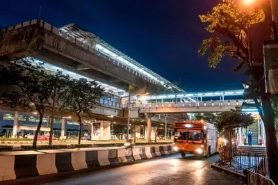 a bus driving down a street under an overpass at night at Rest@Ratchada hotel in Bangkok