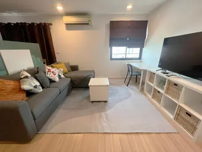 a living room with a couch and a large tv at Central 2BR 3 min walk from BTS Ploen Chit in Makkasan