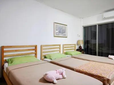 a bedroom with three beds with a stuffed animal on the floor at Maya Suite in Pratunam