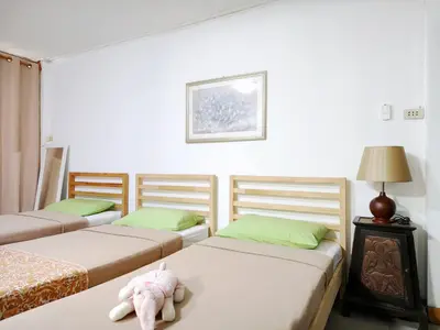 a room with three beds with a stuffed animal on the bed at Maya Suite in Pratunam