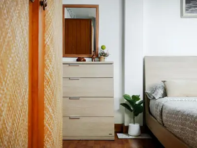 a bedroom with a dresser and a bed with a mirror at Maya Suite in Pratunam