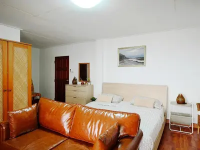 a bedroom with a leather couch and a bed at Maya Suite in Pratunam