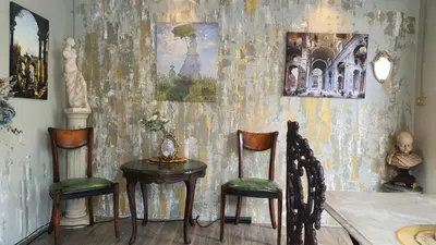 a room with a table and two chairs and paintings at Style Jaritz in Ban Bang Phai