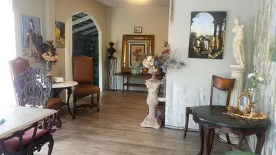 a living room with chairs and tables and paintings on the walls at Style Jaritz in Ban Bang Phai