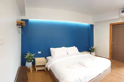 a bedroom with a large bed with a blue wall at Blue Da Bed บลูด้าเบด in Ban Khlong Khwang Klang
