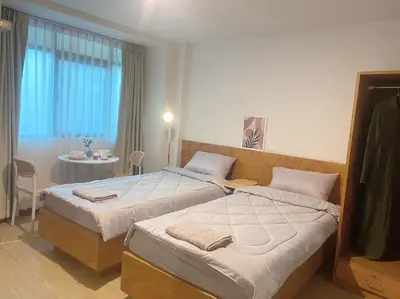 a bedroom with two beds and a table and a window at Jo Hometel in Lak Si