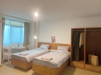 a bedroom with two beds and a room with a table at Jo Hometel in Lak Si