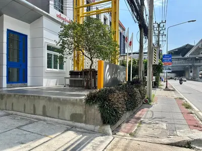 a street corner with a curb with plants on it at Lee's Mark in Samutprakarn