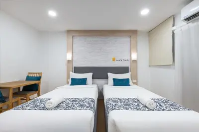 two twin beds in a room with a table at Lee's Mark in Samutprakarn