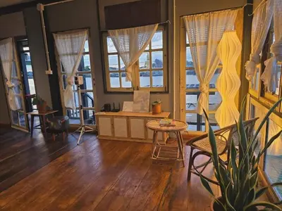 a living room with a table and some windows at เฉื่อยโฮมสเตย์ in Nonthaburi