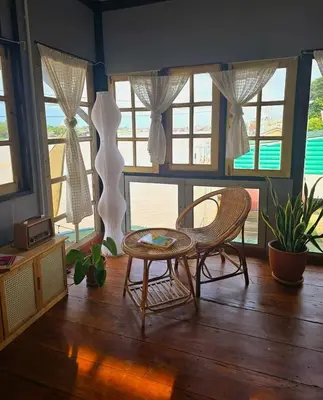 a room with a table and chairs and windows at เฉื่อยโฮมสเตย์ in Nonthaburi