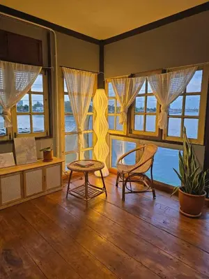 a room with two chairs and a table and windows at เฉื่อยโฮมสเตย์ in Nonthaburi