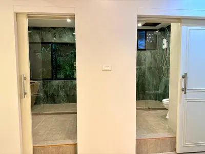 a bathroom with a glass door leading to a toilet at AVALAN PhayaThai airport link in Pratunam