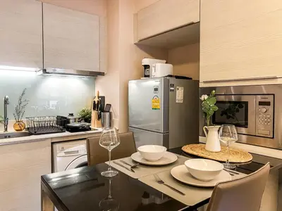 a kitchen with a table with chairs and a refrigerator at Urban High-Rise - Ultra Fast WiFi - BTS Phrom Phong in Bangkok
