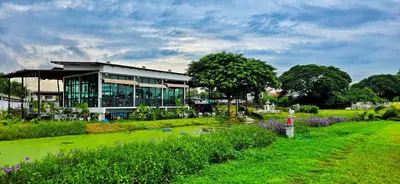 a building with a green field in front of it at Tiny Island Lake Lodge in Bangkok